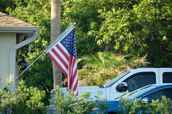 American flag waving on the corner of private residential house, symbol of patriotism.