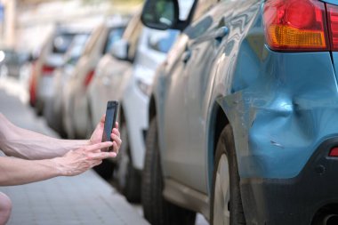 Stresli sürücü, araba kazasından sonra kaza yapan aracın cep telefonu kamerasından acil yardım çağrısı yapıyor. Yol güvenliği ve sigorta kavramı.