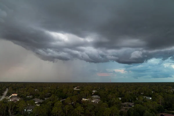 Landscape of dark ominous clouds forming on stormy sky before heavy thunderstorm over rural town area.