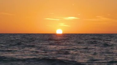 Ocean sunset. Big white sun on dramatic bright sky background, soft evening horizont over sea dark water.