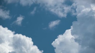 Beyaz kabarık kümülüs bulutlarının zamanı yaz mavi gökyüzünde şekilleniyor. Hareket eden ve değişen bulutlu hava durumu.