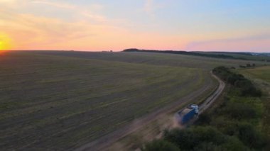 Tarım buğday tarlaları arasında toprak yolda giden kargo kamyonunun hava görüntüsü çok toz yapıyor. Hasat mevsiminde hasatçıların topladığı tahıl naklinden sonra..