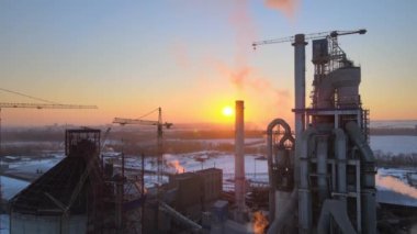 Gün batımında endüstriyel üretim alanında yüksek beton yapılı çimento fabrikası kulesinin havadan görüntüsü. Üretim ve küresel sanayi kavramı.