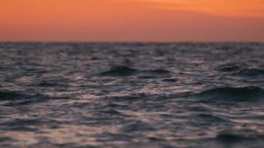 Dramatic red ocean waves at sunset with soft evening sea dark water.