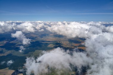 Dünya 'nın yüksek irtifasında, yağmur fırtınasından önce oluşan kabarık kümülüs bulutlarıyla kaplı uçak penceresinden hava görüntüsü.