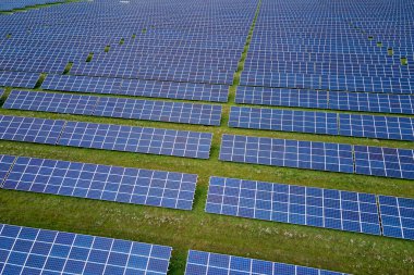 Temiz elektrik enerjisi üretmek için sıra sıra güneş fotovoltaik panelleri olan sürdürülebilir büyük elektrik santralinin havadan görünüşü. Sıfır emisyonlu yenilenebilir elektrik kavramı.