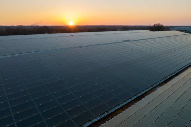 Sanayi binasının çatısına yeşil ekolojik elektrik üretmek için monte edilmiş mavi fotovoltaik panelli güneş enerjisi santralinin hava görüntüsü. Sürdürülebilir enerji konsepti üretimi.