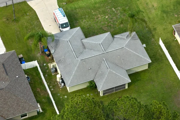 Tipik modern Amerikan özel evinin çatısı asfalt kiremitlerle ve bahçedeki yeşil çimlerle kaplı..