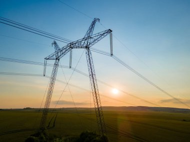 Güneş doğarken elektrik hatları olan yüksek voltajlı kulelerin koyu gölgesi..