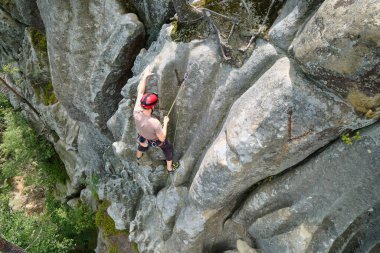 Kararlı dağcı kayalık dağın dik duvarına tırmanıyor. Sporcu zor yolu aştı. Ekstrem sporlar ve kaya tırmanışı hobileri..
