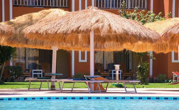 Sillas Cubierta Vacías Bajo Sombrillas Paja Lado Piscina Complejo Tropical —  Fotos de Stock