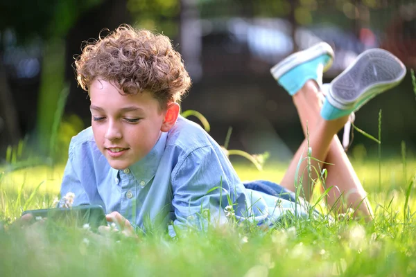 夏の公園で屋外でスマートフォンを閲覧している少年 レジャーや教育の概念のための携帯電話を使用して — ストック写真