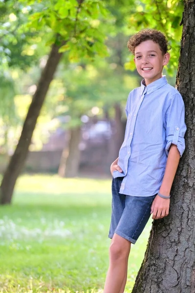 Молодий Щасливий Хлопчик Розслабляється Літньому Парку Спираючись Стовбур Дерева Позитивний — стокове фото