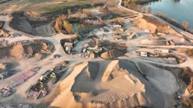 Kazı araçları ve çöp kamyonlarıyla inşaat endüstrisi için kireçtaşı malzemelerinin açık maden sahasının hava görüntüsü.