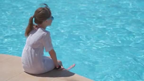夏の晴れた日には澄んだ青い水でプールサイドに休んで白いドレスの若い喜びの子供の女の子 熱帯休暇の概念 — ストック動画