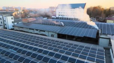 Sanayi binasının çatısına yeşil ekolojik elektrik üretmek için monte edilmiş mavi fotovoltaik panelli güneş enerjisi santralinin hava görüntüsü. Sürdürülebilir enerji konsepti üretimi.