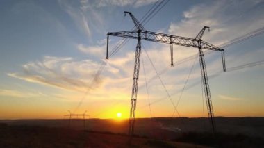 Güneş doğarken elektrik hatları olan yüksek voltaj kulesinin koyu gölgesi. Elektrik enerjisi konsepti aktarımı.