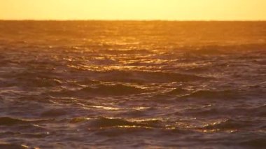 Dramatic bright red sky at ocean sunset, soft evening clouds over sea dark water.