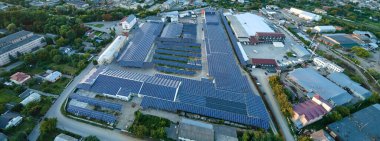 Sanayi binasının çatısına yeşil ekolojik elektrik üretmek için monte edilmiş mavi fotovoltaik panelli güneş enerjisi santralinin hava görüntüsü. Sürdürülebilir enerji konsepti üretimi.