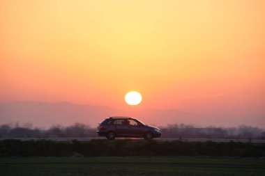Gün batımında şehir içi yolda hızlı giden bir araba. Akşamları otoyol trafiği.