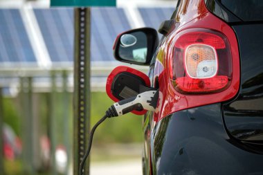 Şehrin caddesinde park halindeki güneş enerjisi yenilenebilir enerji kaynağından elektrik yüklü bir elektrik prizi..