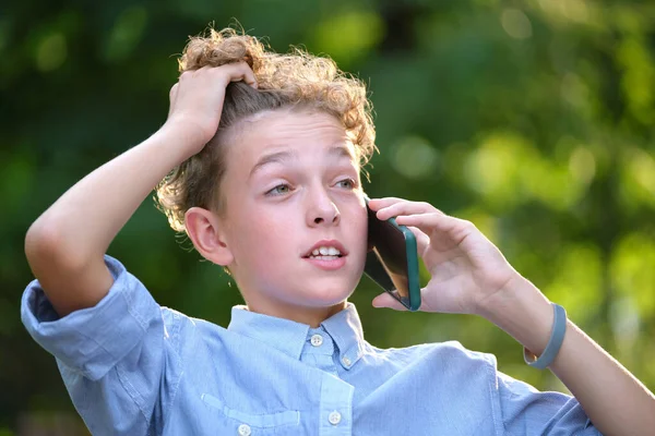 夏の公園で屋外の携帯電話で話をしながら 若い男の子が議論している 10代のコンセプトにおける紛争状況 — ストック写真