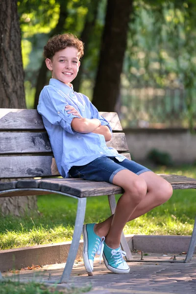 年轻快乐的男孩坐在夏季公园的长椅上放松 积极的孩子在外面享受夏天的时光 儿童福利概念 — 图库照片