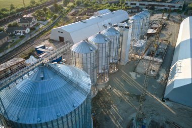 Uzun vadeli tahıl ve yağ tohumu depolamak için endüstriyel havalandırmalı siloların havadan görüntüsü. Tarım bölgesinde buğday kurutmak için metal asansör.