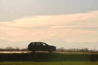 Gün batımında şehir içi yolda hızlı giden bir araba. Akşamları otoyol trafiği.