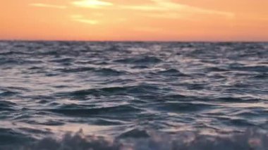 Dramatic bright red sky at ocean sunset, soft evening clouds over sea dark water.