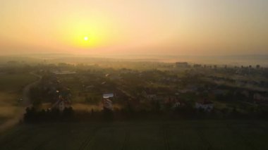 Aerial view foggy sunrise over residential houses in suburban rural area.