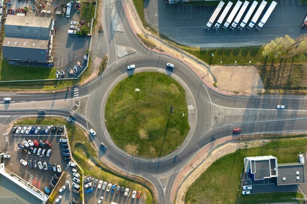 Aerial view of road roundabout intersection with moving heavy traffic. Urban circular transportation crossroads.