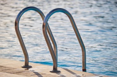 Yüzme havuzuna yakın paslanmaz çelik korkuluklar kaplumbağaların temiz havuz suyuna iniyor. Eğlence etkinlikleri kavramının erişilebilirliği.