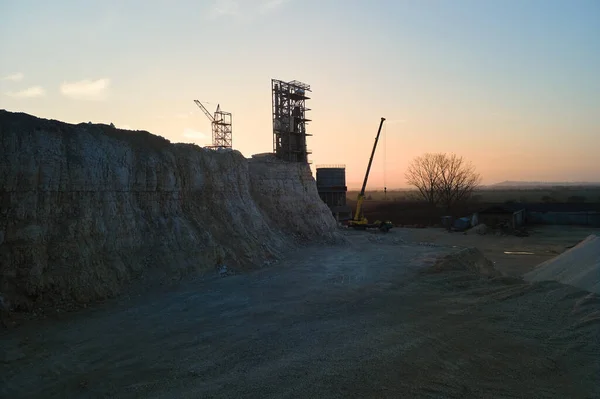 Cement factory at open pit mining of construction sand stone materials. Digging of gravel resources at quarry at sunset.