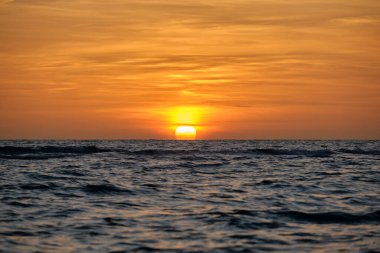 Okyanus batımı. Büyük beyaz güneş dramatik parlak gökyüzü arka planında, yumuşak akşam ufku denizin üstünde karanlık su üzerinde..