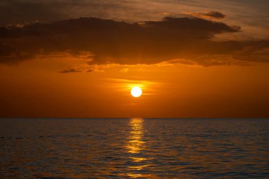 Okyanus batımı. Büyük beyaz güneş dramatik parlak gökyüzü arka planında, yumuşak akşam ufku denizin üstünde karanlık su üzerinde..