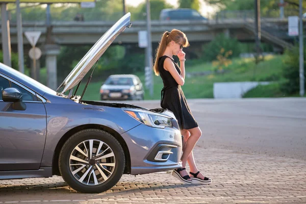 Kaputu ve bozuk motoruyla şehir sokağında duran üzgün kadın şoför yol yardımının gelmesini bekliyor..