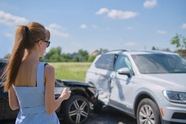 Stressed woman driver standing on street side shocked after car accident. Road safety and insurance concept.