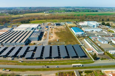 Güneş panellerinin hava görüntüsü park yerinin üzerine gölge çatısı olarak yerleştirilmiş ve temiz elektriğin etkin üretimi için park edilmiş arabalar var. Fotovoltaik teknoloji şehir altyapısına entegre edildi.