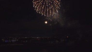 Aerial view of bright fireworks exploding with colorful lights over sea shore on US Independence day holiday.