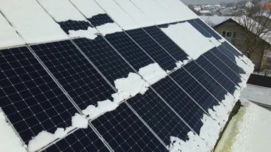 Aerial view of house roof with solar panels covered with snow melting down in winter end for producing clean energy. Concept of low effectivity of renewable electricity in northern region.