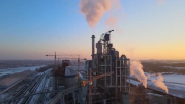 Gün batımında endüstriyel üretim alanında yüksek beton yapılı çimento fabrikası kulesinin havadan görüntüsü. Üretim ve küresel sanayi kavramı.