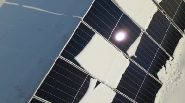 Aerial view of electrical power plant with solar panels covered with snow melting down in winter end for producing clean energy. Concept of low effectivity of renewable electricity in northern region.