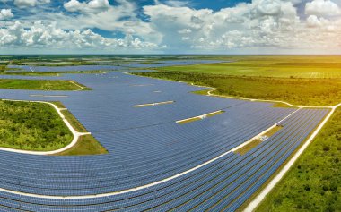 Temiz elektrik enerjisi üretmek için sıra sıra güneş fotovoltaik panelleri olan sürdürülebilir büyük elektrik santralinin havadan görünüşü. Sıfır emisyonlu yenilenebilir elektrik kavramı.