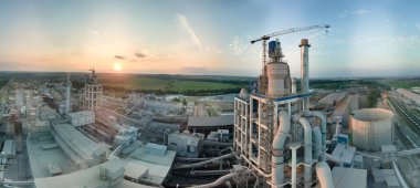 Yüksek fabrika yapısı olan çimento fabrikası ve endüstriyel üretim bölgesinde kule vinçleri var. Üretim, küresel sanayi ve hava kirliliği kavramı.