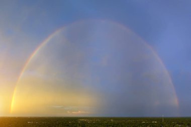 Colorful round rainbow against blue evening sky after heavy thunderstorm.