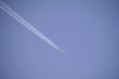 Mesafeli yolcu jet uçağı açık mavi gökyüzünde yüksek irtifada uçarken ardında beyaz duman izi bırakıyor. Hava taşımacılığı kavramı.