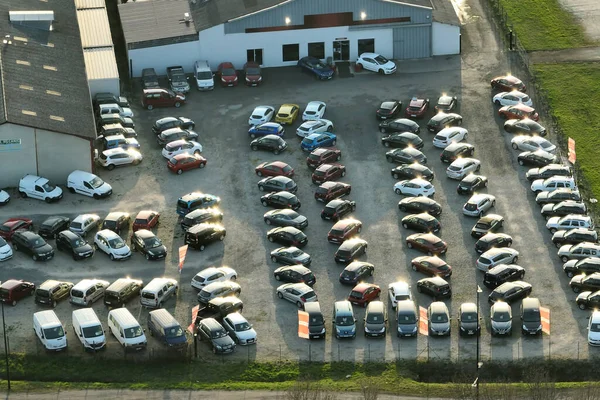 Aerial view of many colorful cars parked on dealer parking lot for sale.