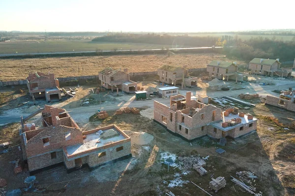 Aerial view of new homes with brick framework walls under construction in rural suburban area. Development of real estate in modern city suburbs.