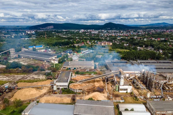 Aerial view of wood processing factory with smoke from production process polluting atmosphere at plant manufacturing yard.